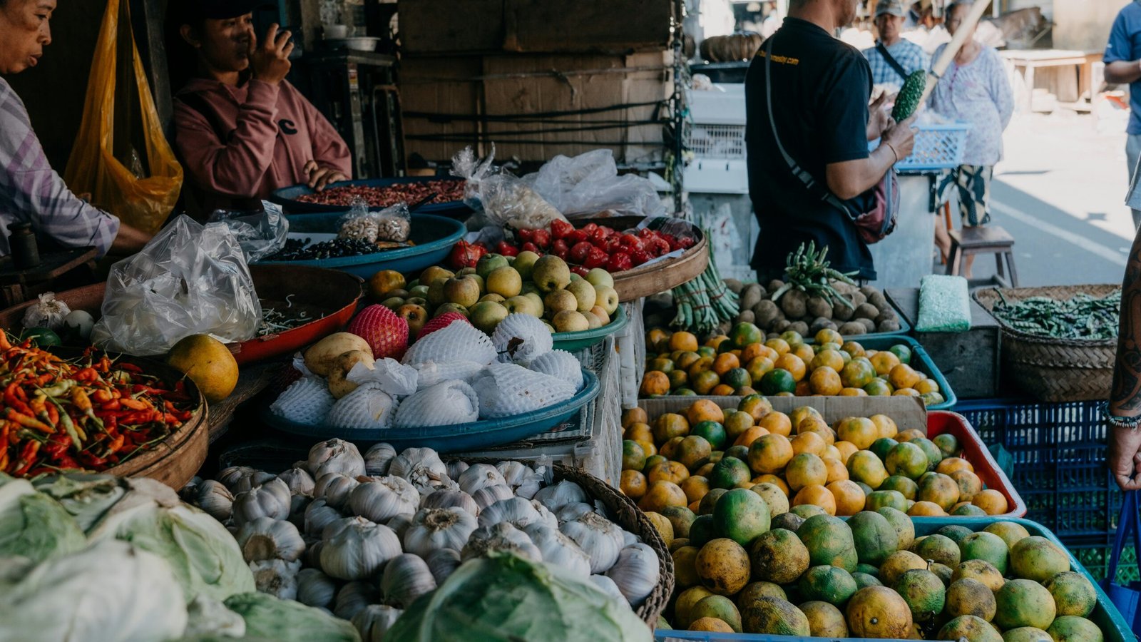 a group of people standing around a table filled with fruits and vegetables